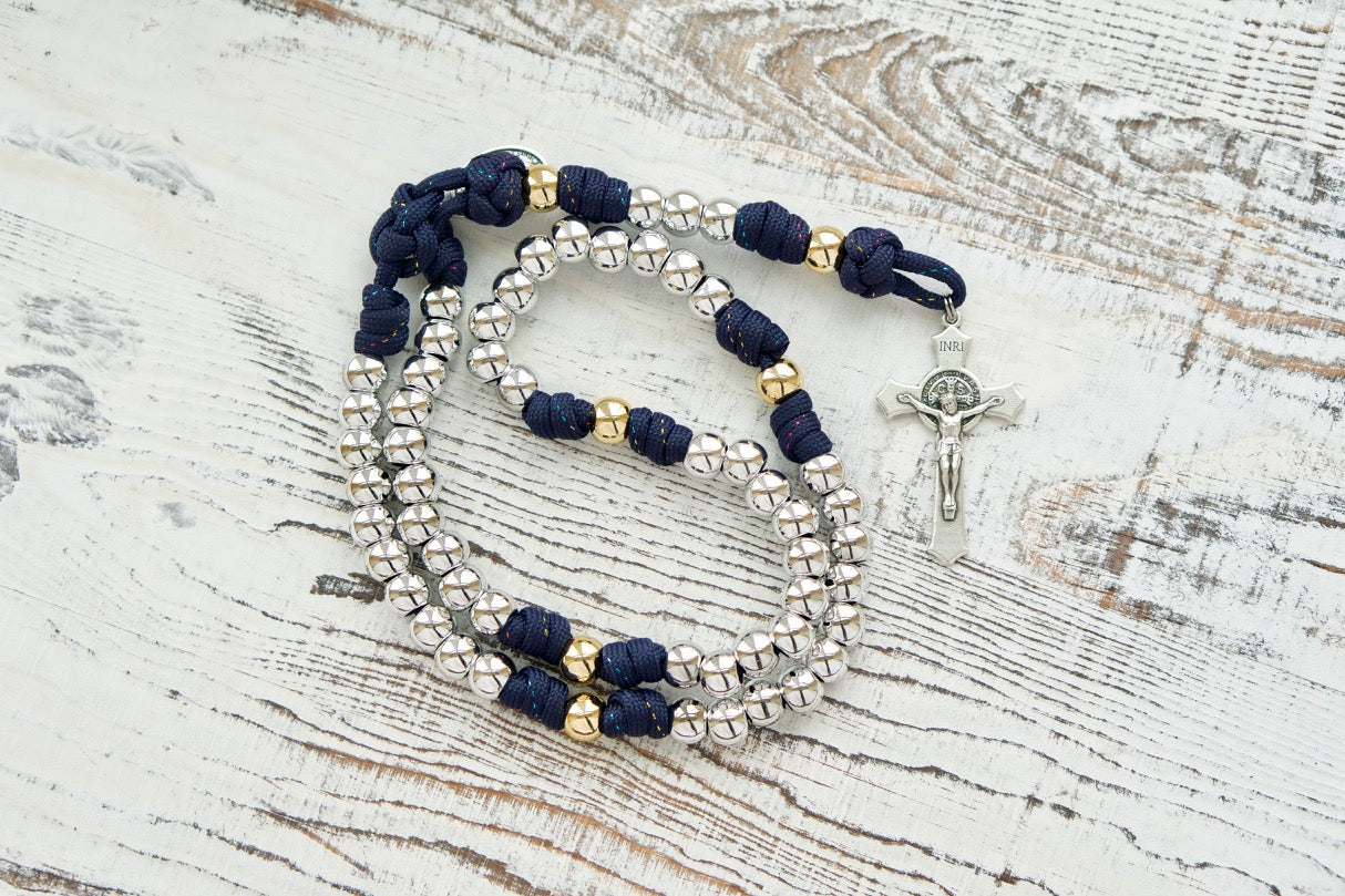 Dark blue paracord rosary with silver Hail Mary beads and gold Our Father beads, adorned with a St. Benedict Crucifix and Miraculous Medal, perfect for spiritual strength and prayer.