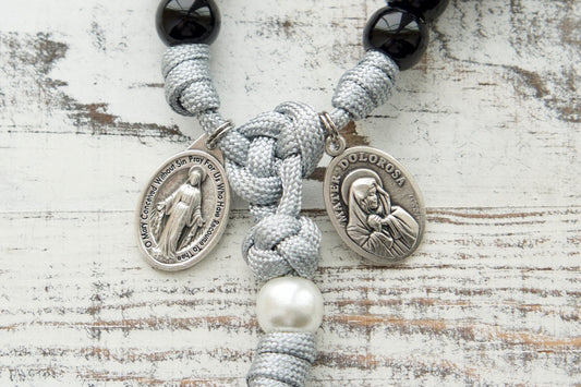 Mater Dolorosa - Our Lady of Sorrows - 7 Sorrows Paracord Rosary, handmade by a small Catholic family. Features black, grey, and white colors, 2" silver Pardon Crucifix, Miraculous Medal, and Mater Dolorosa/Ecce Homo medal.