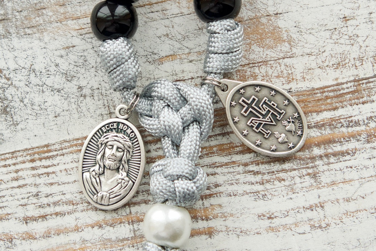 Mater Dolorosa - Our Lady of Sorrows - 7 Sorrows Paracord Rosary featuring black, grey, and white colors, 20-inch length, silver 2" Pardon Crucifix, Miraculous Medal, and Mater Dolorosa/Ecce Homo medal.