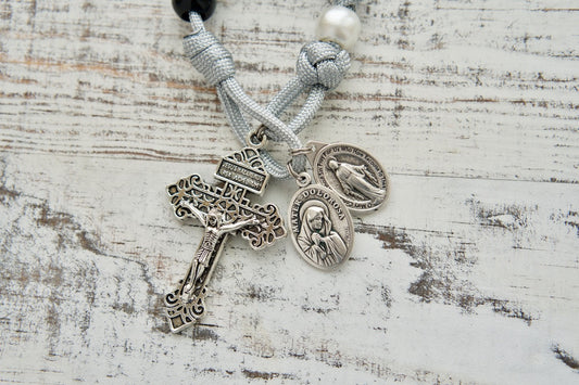 Mater Dolorosa - Our Lady of Sorrows - 7 Sorrows Pocket Paracord Rosary, featuring black, grey, and white colors; 2" silver pardon crucifix; Miraculous Medal and Mater Dolorosa/Ecce Homo devotional medal. Handmade by a Catholic family for durable and unbreakable prayer support.