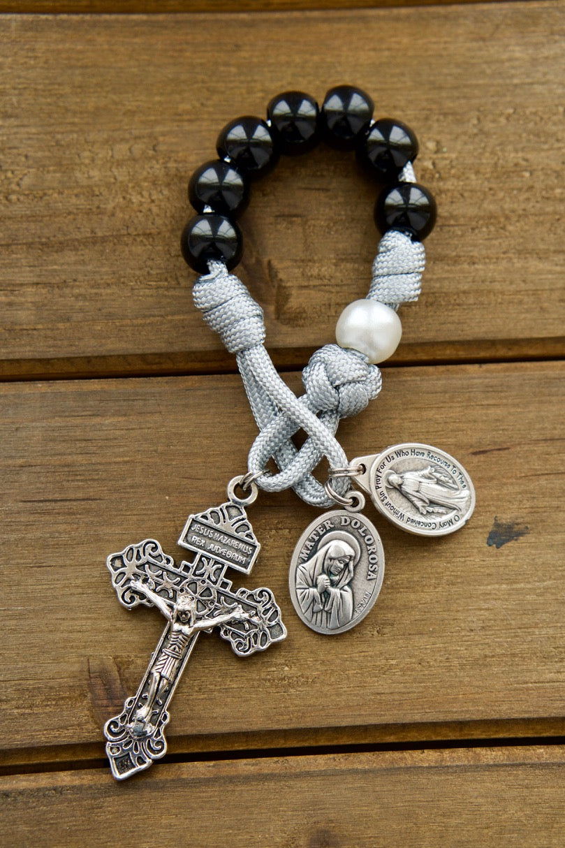 Mater Dolorosa - Our Lady of Sorrows - 7 Sorrows Pocket Paracord Rosary with black, grey, and white colors, featuring a silver 2" Pardon Crucifix and Miraculous Medal paired with a Mater Dolorosa/Ecce Homo medal. Handmade by our small Catholic family of 6 with durable paracord for spiritual strength and protection on life's battles.