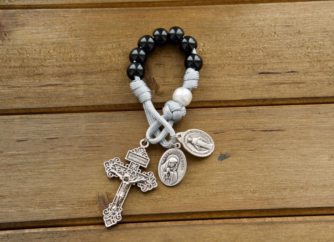 Mater Dolorosa - Our Lady of Sorrows - 7 Sorrows Pocket Paracord Rosary in black, grey, and white colors with a silver 2" Pardon Crucifix, Miraculous Medal, and Mater Dolorosa/Ecce Homo medal. Handcrafted by a Catholic family for spiritual strength and durability.