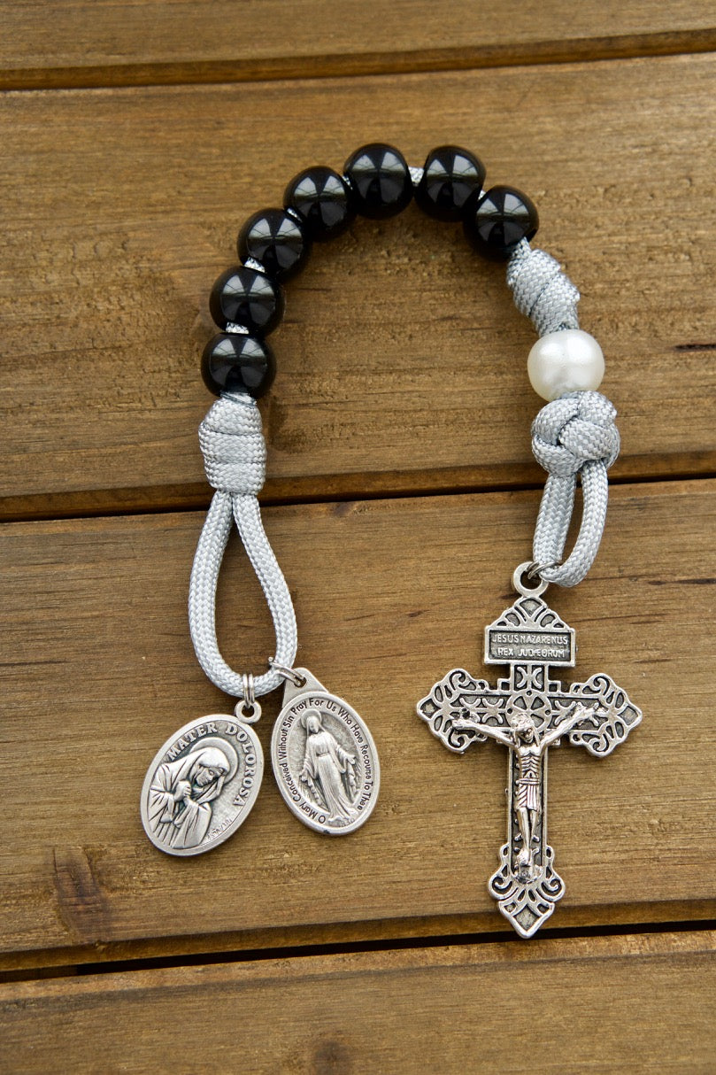 Mater Dolorosa - Our Lady of Sorrows - 7 Sorrows Pocket Paracord Rosary in black, grey, and white colors with a silver 2" Pardon Crucifix and Miraculous Medal paired with a Mater Dolorosa/Ecce Homo medal. Durable, premium, unbreakable paracord rosary for spiritual protection.