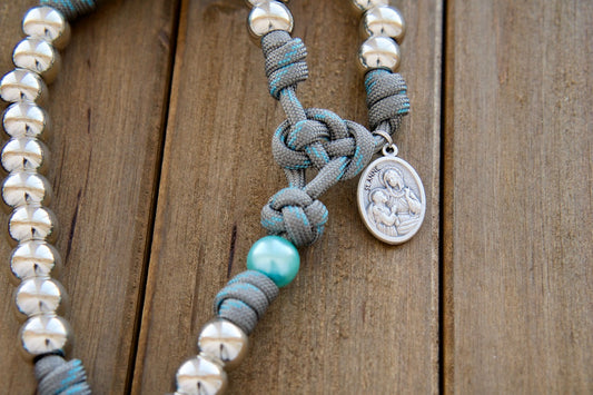 St. Anne's Intercession - Sky Blue, Gray, and Silver 5 Decade Paracord Rosary with silver Hail Mary beads, sky blue Our Father beads, and a devotional St. Anne medal; durable and unbreakable design, handmade by a Catholic family of 6.
