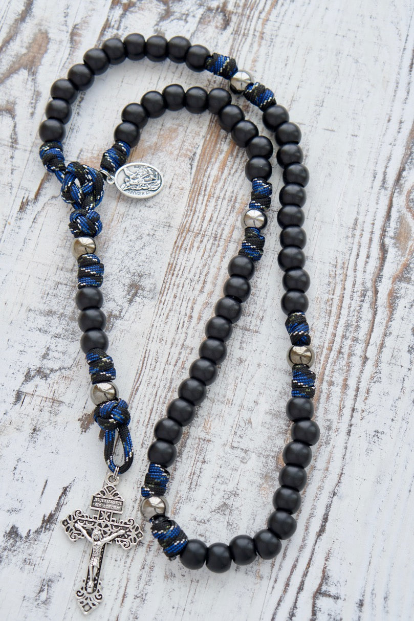 Embrace your faith with our Thin Blue Line - 5 Decade Paracord Rosary, featuring durable and stylish camo rope design. This premium Catholic gift includes matte black Hail Mary beads, gunmetal Our Father beads, Pardon Crucifix, St. Michael & Guardian Angel devotional medal for spiritual protection. Unbreakable paracord rosary for the devoted.