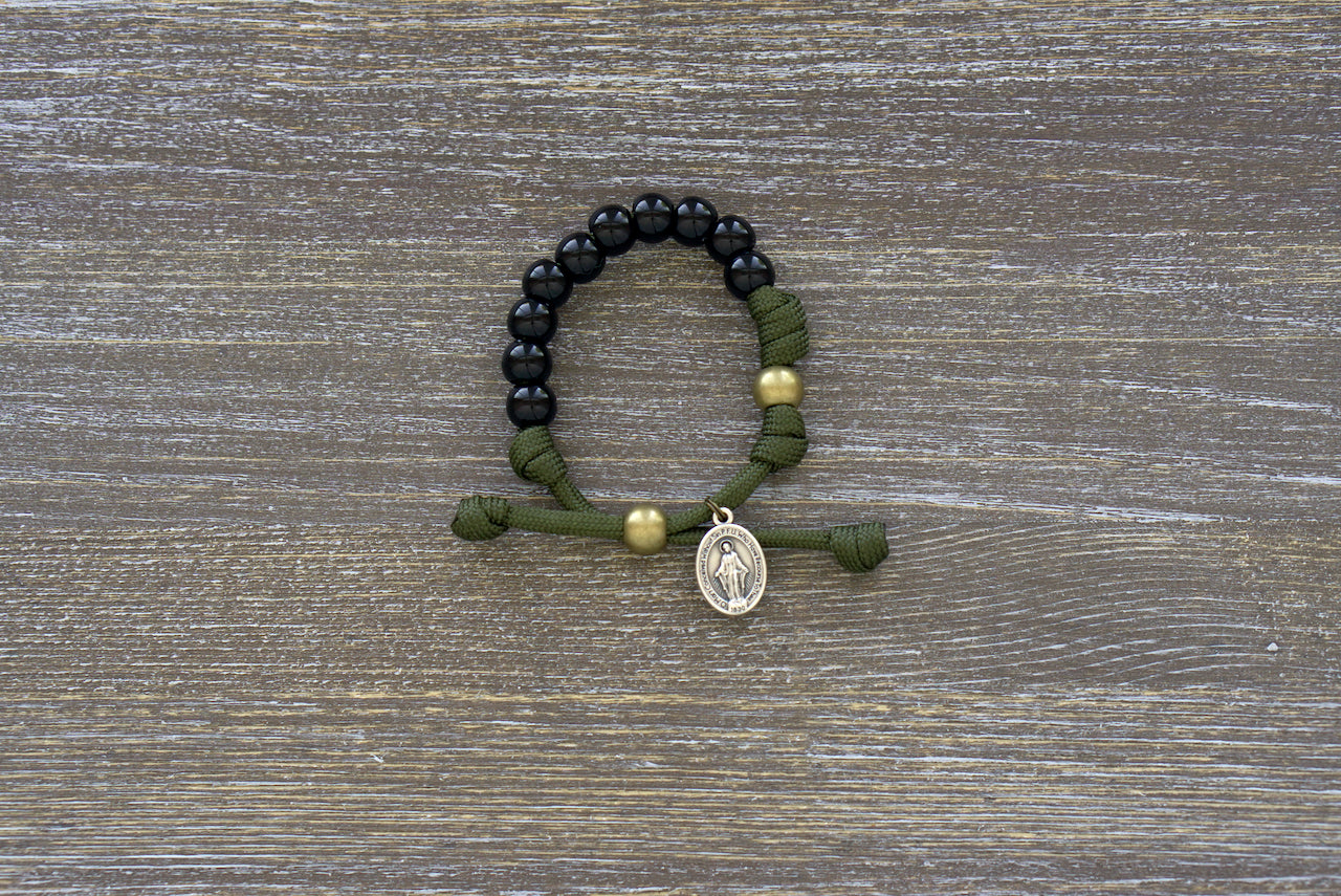 Kid's Army Green and Black Rosary Bracelet featuring black beads, olive Our Father bead, and a small Miraculous Medal; handmade with tradition and faith in mind.