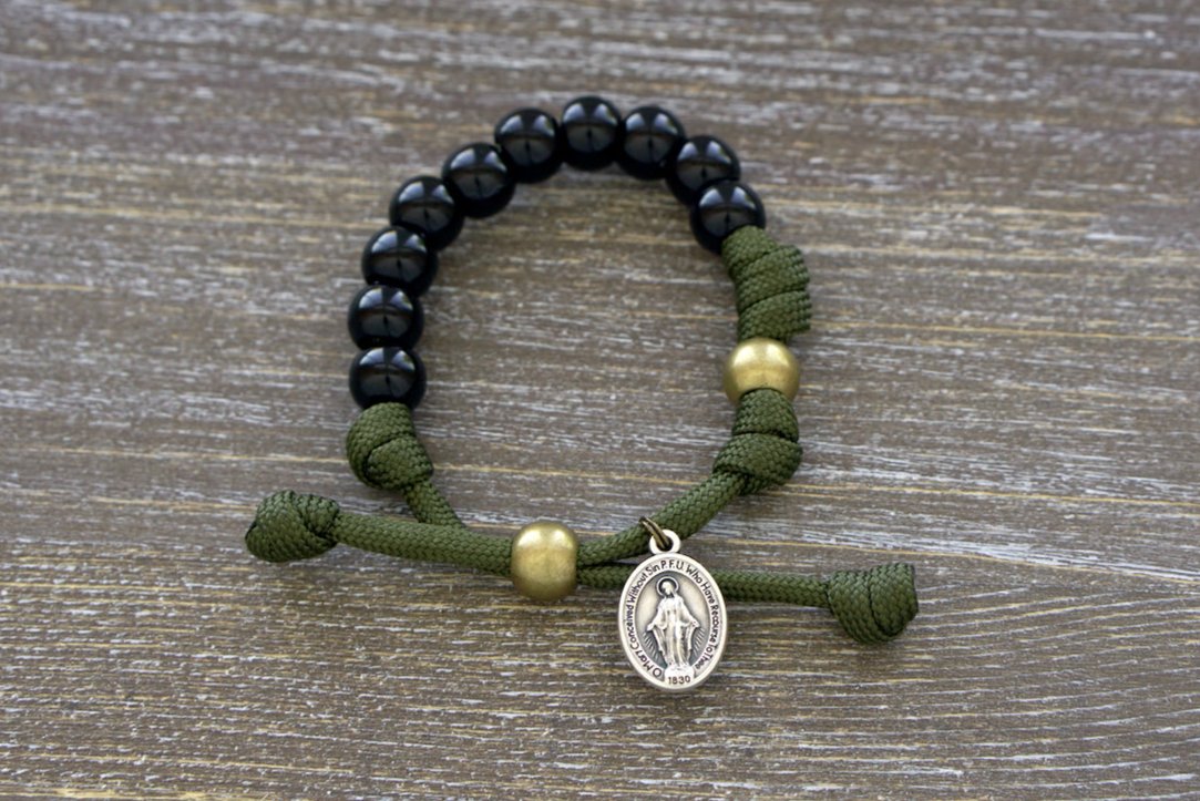 Army Green and Black Kid's Rosary Bracelet, featuring durable paracord rope and black beads for Hail Mary prayers, with an olive Our Father bead and Miraculous Medal.