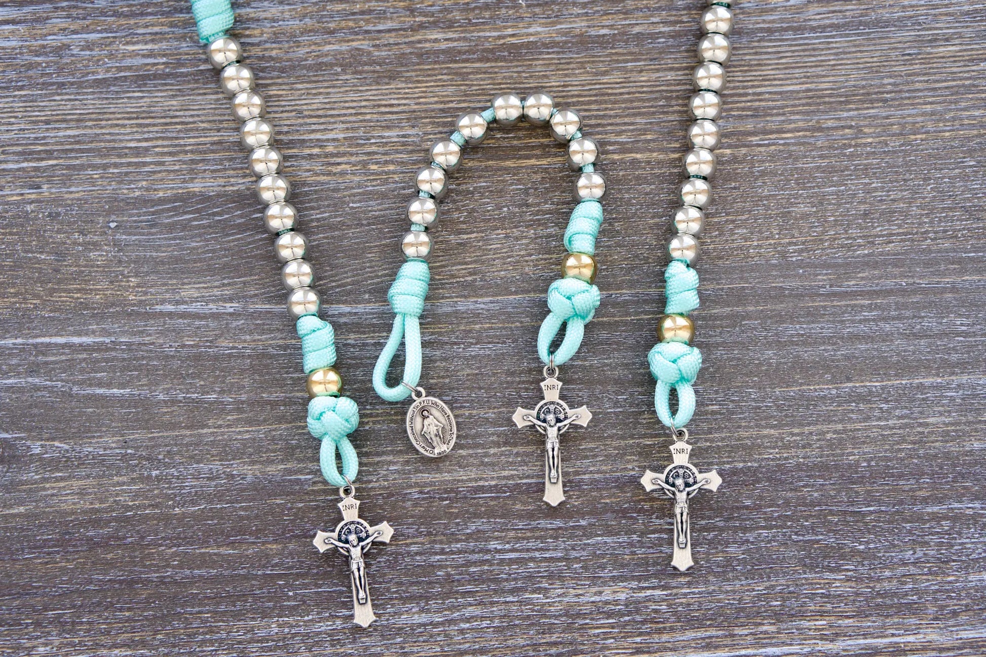 August Queen of the Heavens kids' paracord rosary with teal blue rope, royal silver and gold beads, 2" St. Benedict crucifix, and 3/4 inch Miraculous Medal