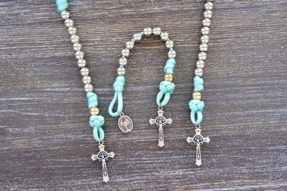 August Queen of the Heavens kids' paracord rosary with teal blue rope, royal silver and gold beads, 2" St. Benedict crucifix, and 3/4 inch Miraculous Medal