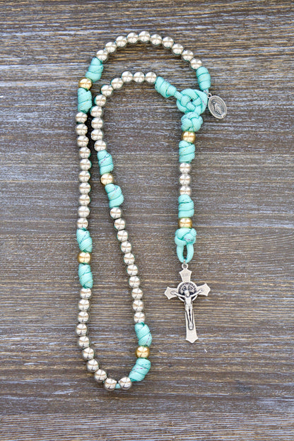 August Queen of the Heavens - Kid's 5 Decade Paracord Rosary: A teal blue paracord rosary with inlaid rainbow ribbon, royal silver and gold 10mm acrylic beads, a 2" St. Benedict crucifix, and a 3/4" Miraculous Medal.