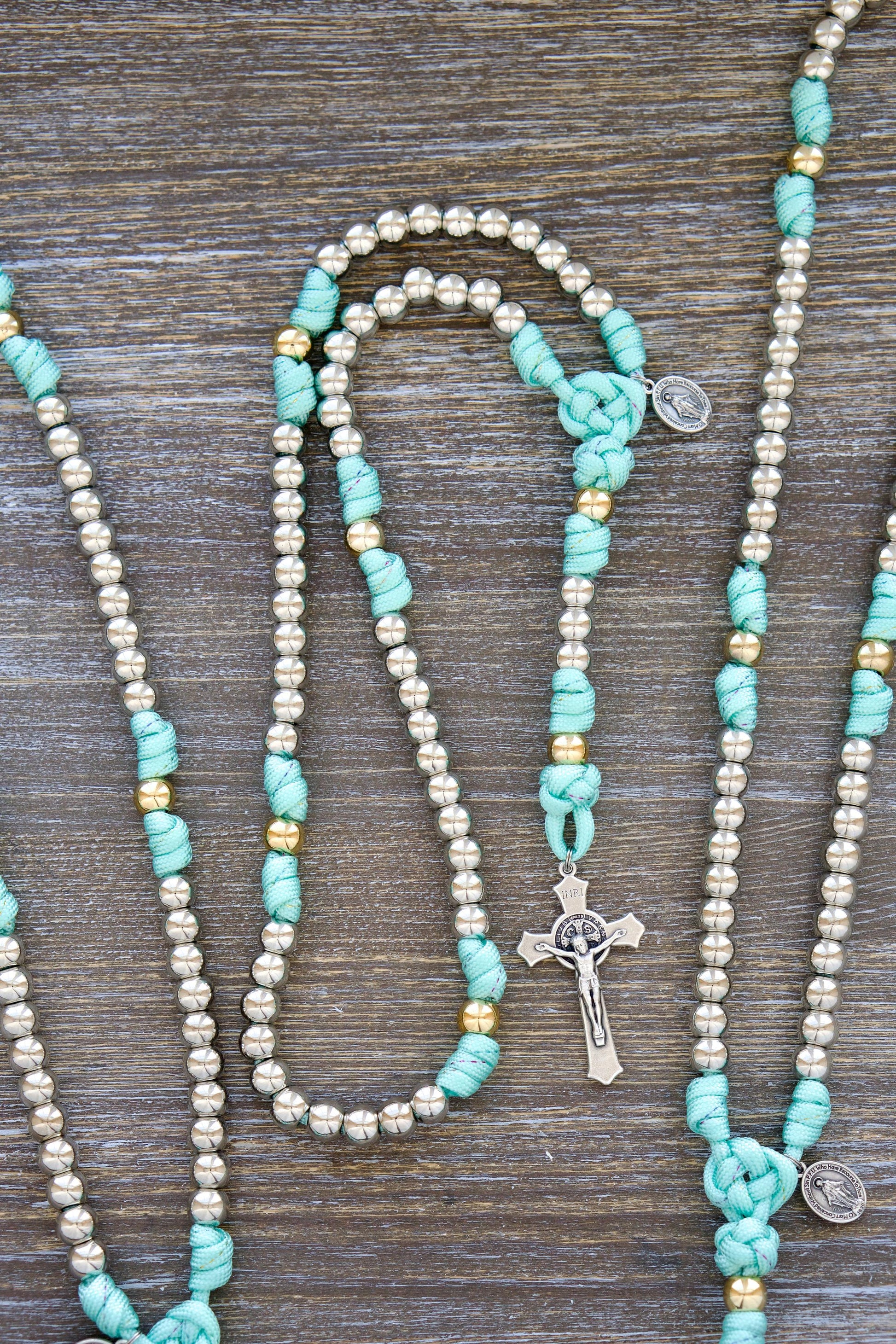 August Queen of the Heavens Kids Rosary - Teal blue paracord with rainbow ribbon, silver/gold 10mm beads, St. Benedict Crucifix, and Miraculous Medal devotional charm. Durable handmade rosary for girls and young women.