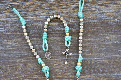 August Queen of the Heavens Kid's Pocket Rosary: Features 10mm acrylic beads, rose gold Our Father bead, silver Hail Mary beads, a petite St. Benedict crucifix, and Miraculous Medal. Handcrafted paracord rosary designed for portability and young hands.