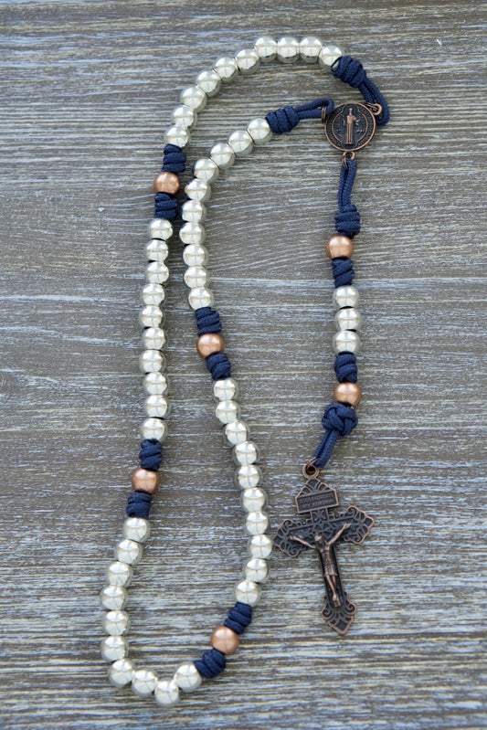 Navy paracord Benedict’s Battle rosary with silver Hail Mary beads, copper Our Father beads, St. Benedict medal, and antique Pardon crucifix.