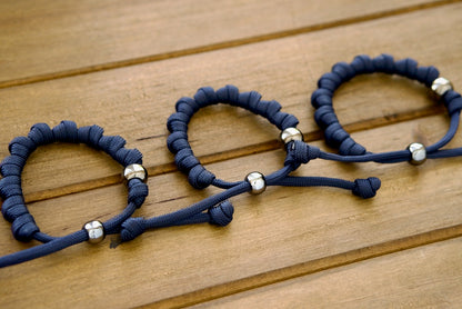 Navy Blue and Gunmetal - Knotted Paracord Rosary Bracelet, featuring durable dark blue paracord 550, adjustable design for all ages, gunmetal beads for an elegant touch, perfect for prayer on-the-go or in any situation, made with paracord 550 and acrylic beads.