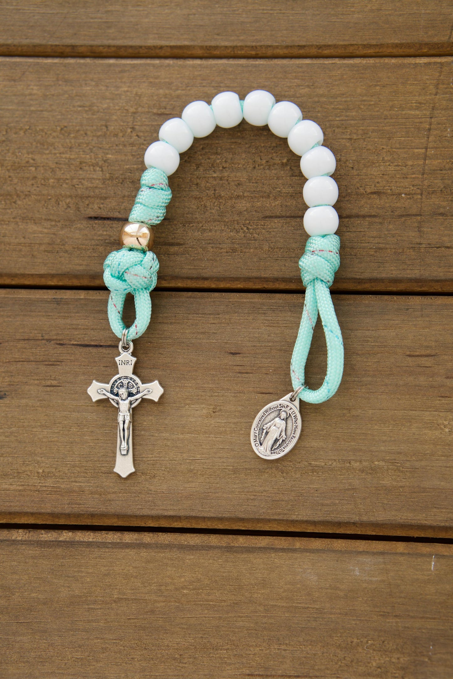 Kid's mint green pocket paracord rosary with white Hail Mary beads, rose gold Our Father beads, St. Benedict Crucifix, and Miraculous Medal - a perfect First Communion or Easter gift for children learning to pray.