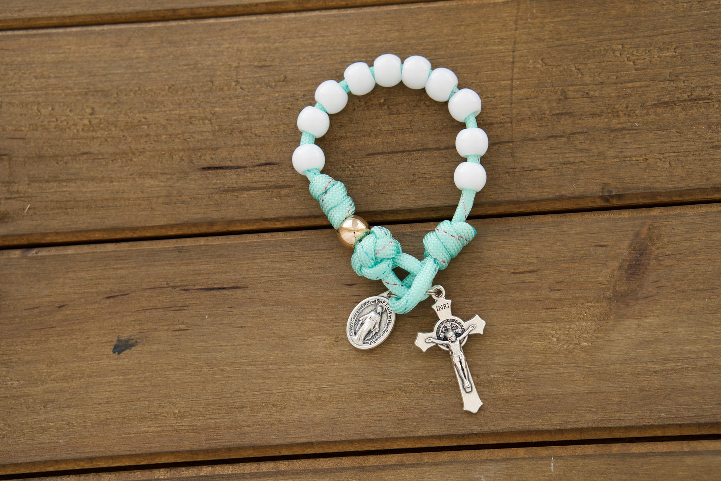 Kids' mint green paracord pocket rosary with white Hail Mary beads and rose gold Our Father beads, featuring a smaller St. Benedict Crucifix and Miraculous Medal, perfect for First Communion or Easter gifts.