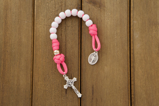 Bright pink paracord rosary with white Hail Mary and rose gold Our Father beads, featuring tiny Miraculous Medal and St. Benedict crucifixes.