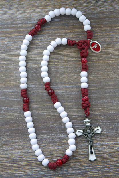 Crimson Shield Rosary: A handmade, five-decade paracord rosary featuring maroon red cord, black or white Hail Mary beads, a gleaming black (or white) St. Benedict crucifix, and a vibrant red Holy Spirit medal.