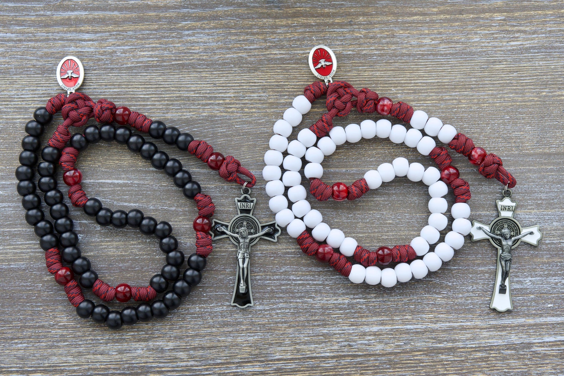 A vibrant maroon red paracord rosary, "The Crimson Shield," featuring black (or white) Hail Mary beads and a gleaming black (or white) enamel St. Benedict crucifix.