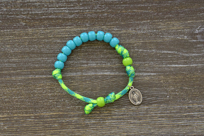 Kid's Rosary Bracelet - David's Slingshot, featuring vibrant lime green and sky blue paracord, with 10mm blue Hail Mary beads, a matching lime green Our Father bead, and a petite Miraculous Medal.