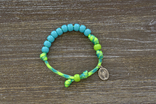 Kid's Rosary Bracelet - David's Slingshot, featuring vibrant lime green and sky blue paracord, with 10mm blue Hail Mary beads, a matching lime green Our Father bead, and a petite Miraculous Medal.