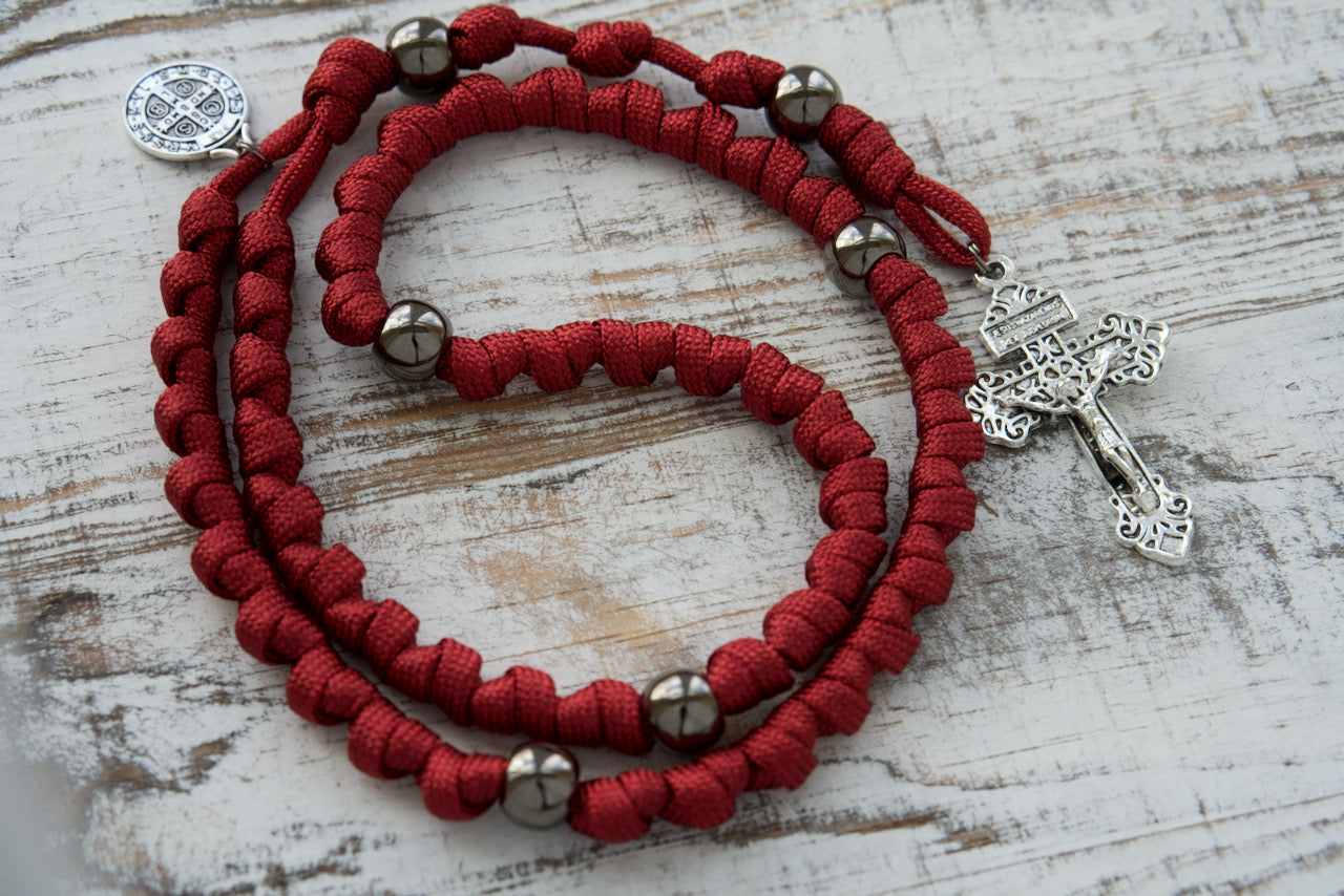 The Defender of Faith - Maroon and Gunmetal Knotted Rope Rosary, your ultimate spiritual weapon! Featuring a sturdy paracord construction, gunmetal beads, and Saint Benedict's protective presence.