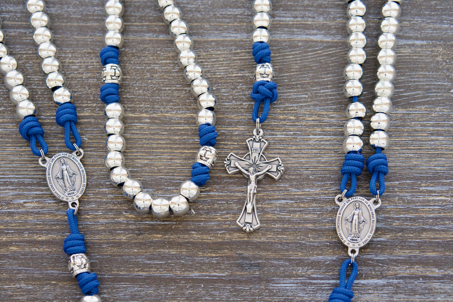 Divine Radiance Premium Metal Paracord Rosary: Close-up image showcasing lustrous 'miraculous blue' paracord, silver metal alloy Hail Mary beads, a shimmering silver Our Father cross barrel bead design, and the centerpiece Miraculous Medal and Crucifix. 