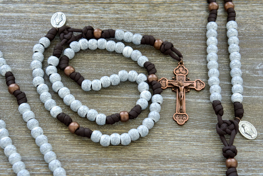 Sanctus Servo's Embrace the Cross - 5 Decade Paracord Rosary, featuring dark brown paracord rope, antique copper Our Father beads, cracked ivory Hail Mary beads, Miraculous Medal devotional medal, and a 3-inch copper 12-Apostles Crucifix.