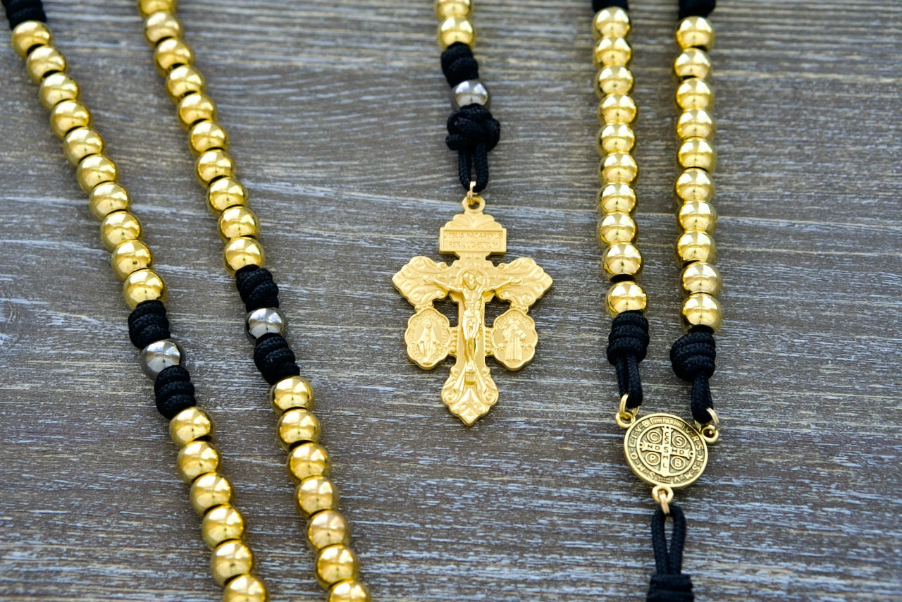 Faith and Valor Metal Premium Paracord Rosary with Gold, Gunmetal and Black beads, featuring a St. Benedict center medal and 'Triple Threat' Pardon crucifix for unbreakable devotion.