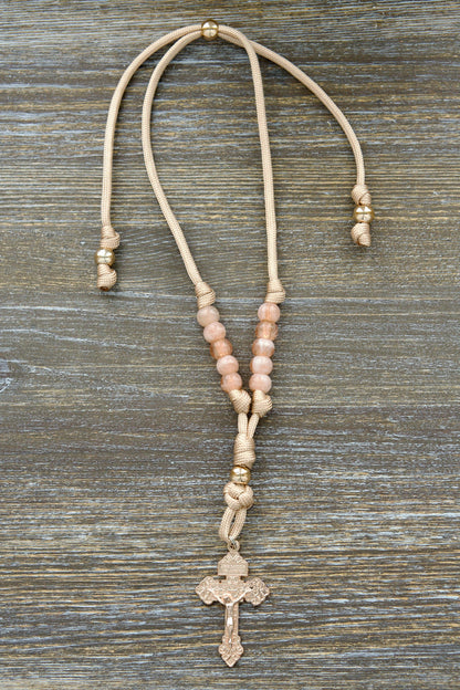 Handmade Gate of Heaven rearview mirror rosary featuring tan/rose gold paracord, a rose gold Our Father bead, milky pink Hail Mary beads, and an exclusive rose gold Pardon crucifix centerpiece.