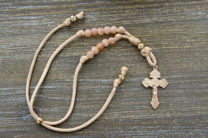 Gate of Heaven Rearview Mirror Rosary: A handmade paracord rosary with rose gold accents and milky pink beads, featuring a unique pardon crucifix centerpiece. Designed for car use.