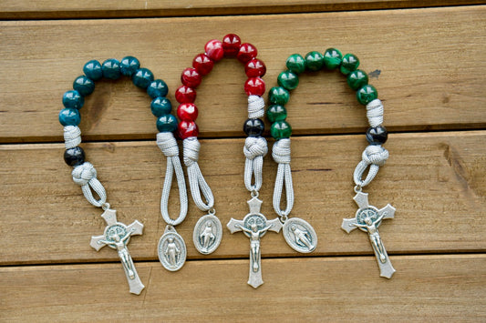 A colorful and powerful single decade rosary made of premium paracord rope, adorned with gemstone colored beads, and featuring a Miraculous Medal and St. Benedict Crucifix for added protection. Available in three captivating colors: Garnet Red, Emerald Green, or Ingolight Blue.