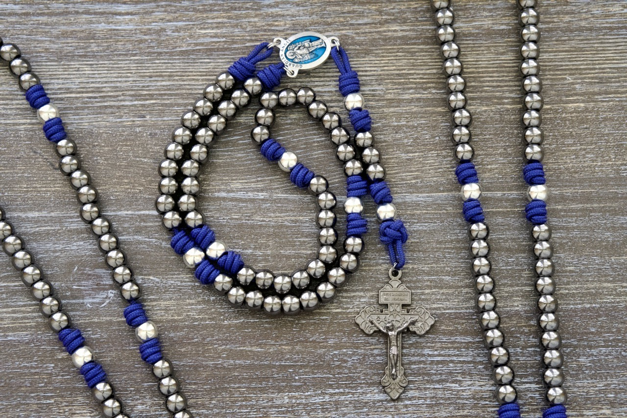 A Premium Catholic Gift for Your Spiritual Battles. Beautiful royal blue paracord with durable gunmetal and silver alloy beads and a stunning blue enamel Guardian Angel centerpiece.
