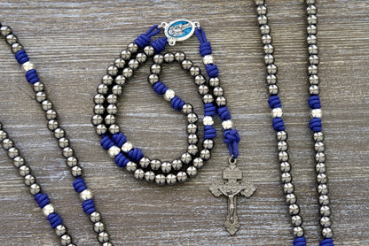 A Premium Catholic Gift for Your Spiritual Battles. Beautiful royal blue paracord with durable gunmetal and silver alloy beads and a stunning blue enamel Guardian Angel centerpiece.