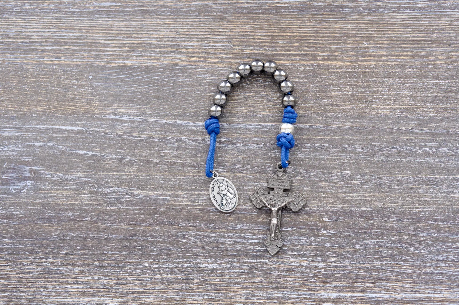 Guardian of Grace pocket paracord rosary with blue rope, gunmetal crucifix, and silver alloy beads – premium metal beaded design.