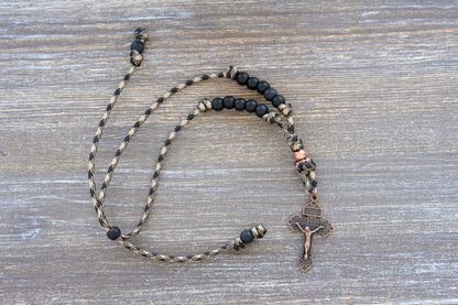 Heavy Duty Hail Mary rearview mirror rosary hangs securely, showcasing 10mm matte black and antique copper beads on rugged 550 paracord with a copper crucifix.