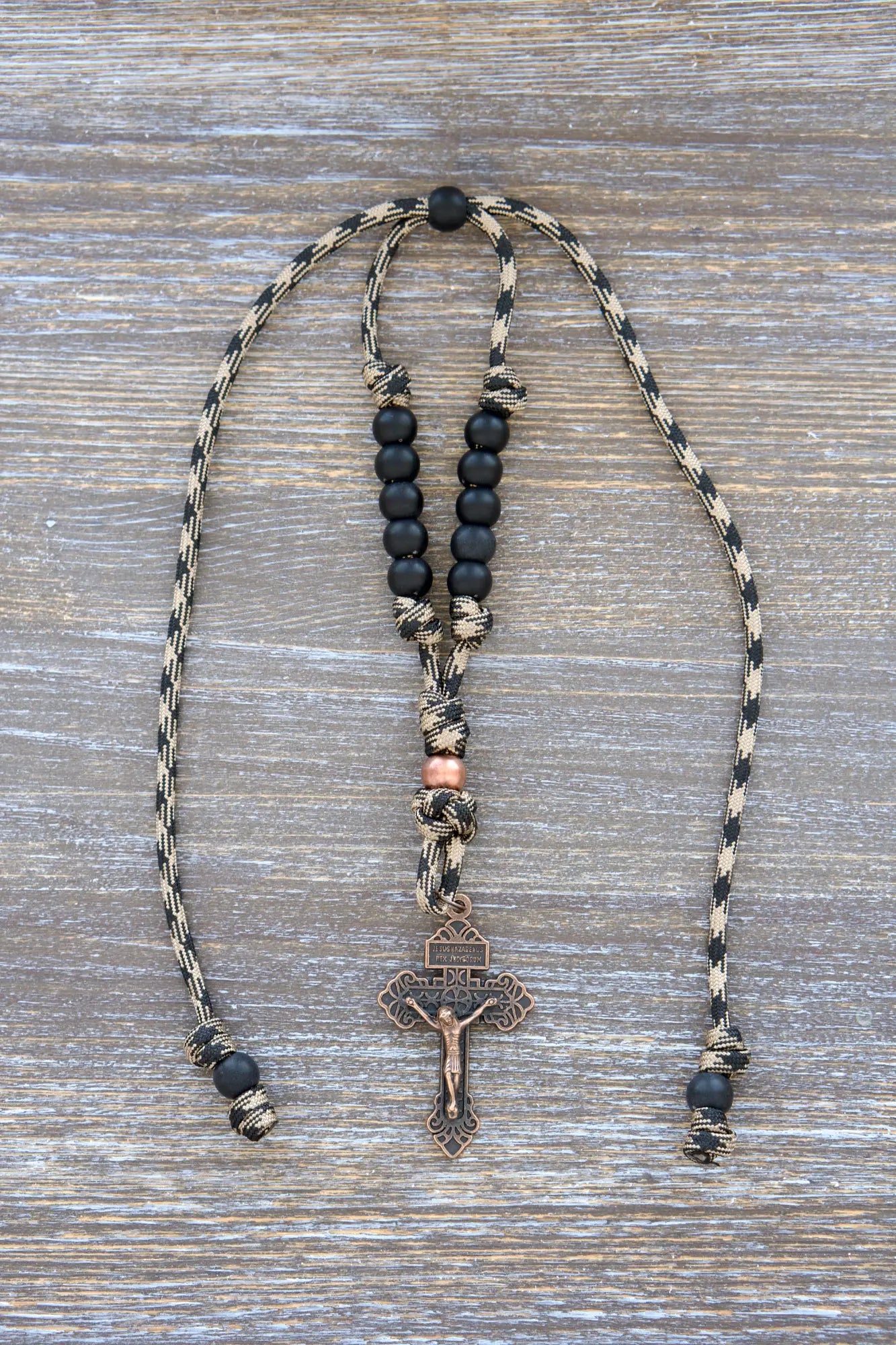 Heavy Duty Hail Mary mirror rosary with camo black and brown paracord, matte black and antique copper beads, hanging securely from a rearview mirror.