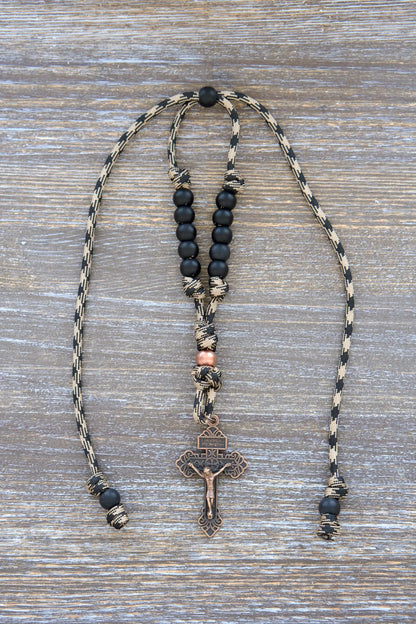 Heavy Duty Hail Mary mirror rosary with camo black and brown paracord, matte black and antique copper beads, hanging securely from a rearview mirror.