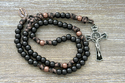 Heavy Duty Hail Mary - 5 Decade Paracord Rosary featuring a black enamel St. Benedict crucifix, large acrylic beads, and military-inspired camo paracord in copper and coffee hues.