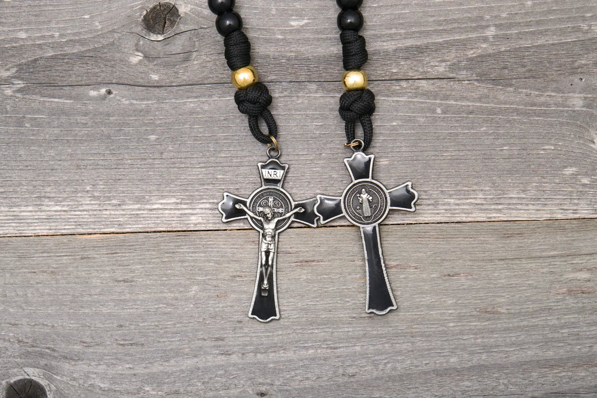 The Holy Servant Rosary features black paracord, gold beads, and a large enamel St. Benedict crucifix.