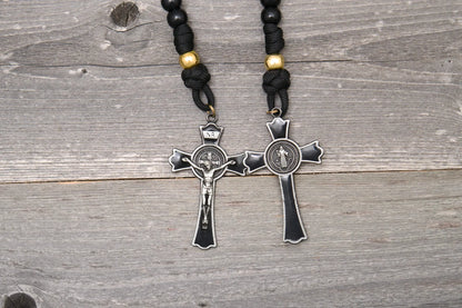 The Holy Servant Rosary features black paracord, gold beads, and a large enamel St. Benedict crucifix.