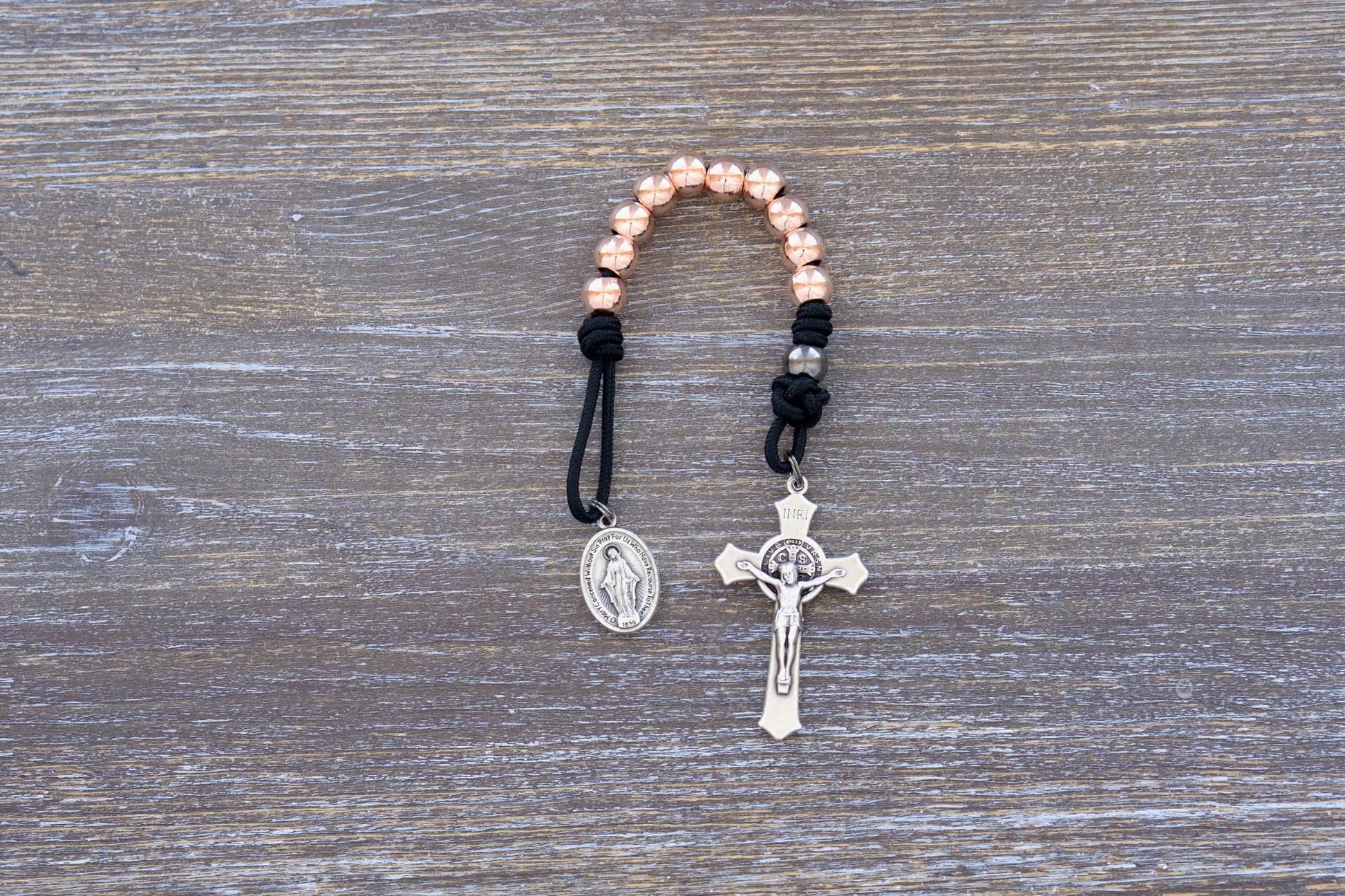 Immaculate Strength premium metal paracord rosary featuring black rope and rose gold beads, sleek and durable.