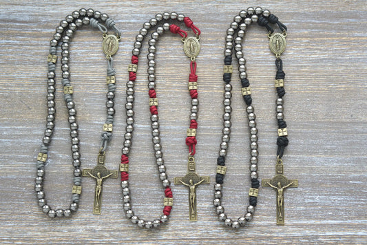 Three handcrafted paracord rosaries with olive crusader beads, gunmetal Hail Mary beads, a Miraculous Medal centerpiece, and a St. Benedict crucifix.  