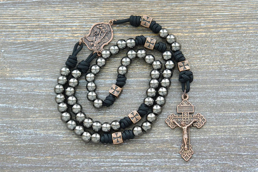 Gunmetal metal alloy Hail Mary beads on midnight black paracord with a St. Michael centerpiece and crucifix adorn this rugged rosary. 