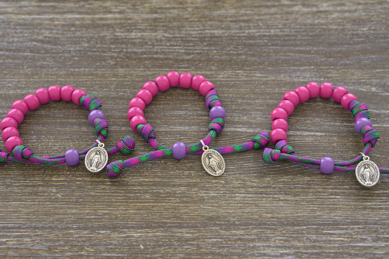 Judith's Sword - Kids Rosary Bracelet by Sanctus Servo. Vibrant purple and green paracord, 10mm pink Hail Mary beads, petite Our Father and Miraculous Medal. 