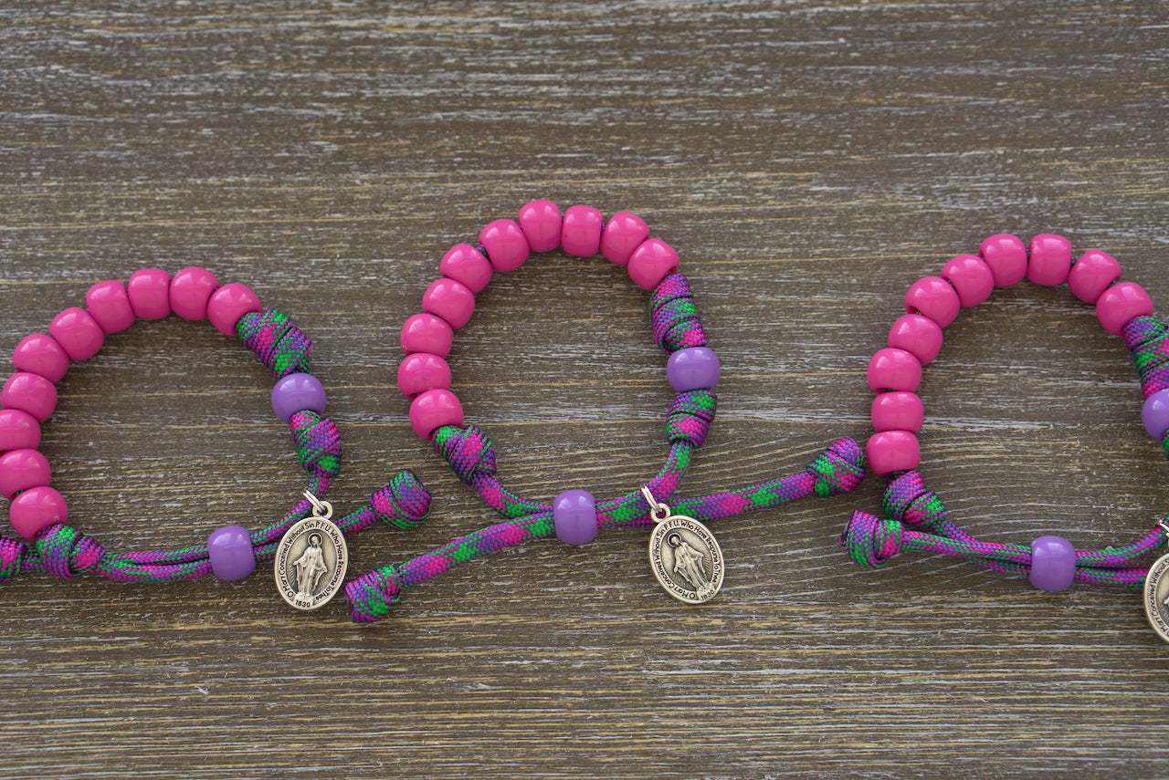 Kid's Rosary Bracelet, Judith's Sword - Paracord Bracelet by Sanctus Servo in vibrant purple and green with pink Hail Mary beads, petite Our Father bead, and Miraculous Medal.