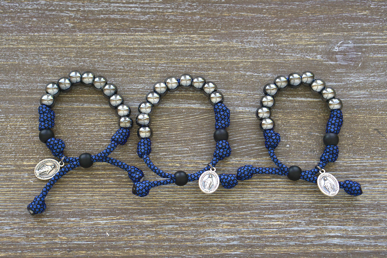 Kid's Blue and Gunmetal Rosary Bracelet, featuring navy blue paracord, black Our Father bead, 10mm gunmetal Hail Mary beads, and a small Miraculous Medal, perfect for strengthening faith through prayer.