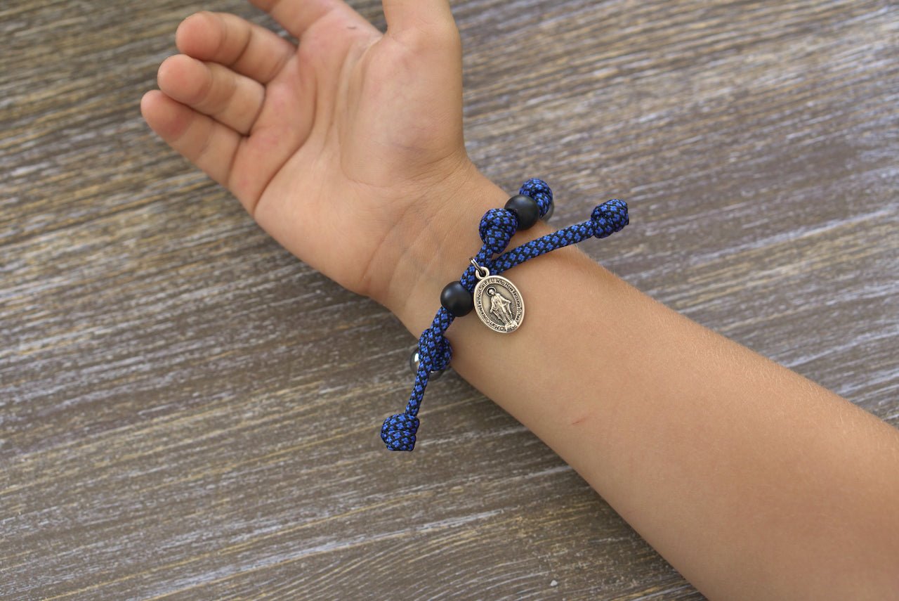 Blue and Gunmetal Kid's Rosary Bracelet, featuring navy blue and black paracord, gunmetal beads for Hail Mary prayers, black Our Father bead, Miraculous Medal.