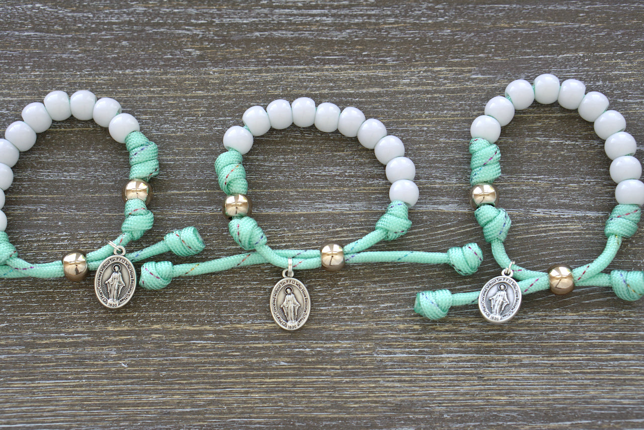 Children's Mint Green Kid's Rosary Bracelet by Sanctus Servo, featuring rainbow ribbon and rose gold Our Father bead for young Catholics on their spiritual journey.