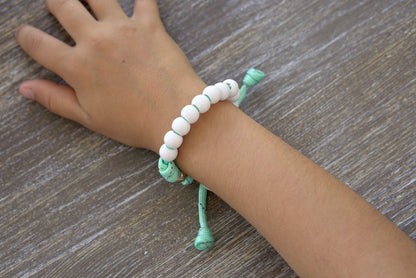 Children's Mint Green Kid's Rosary Bracelet from Sanctus Servo - a handmade, colorful spiritual weapon featuring rainbow ribbon intertwined with paracord and beads, adorned with a rose gold Our Father bead and a tiny Miraculous Medal.